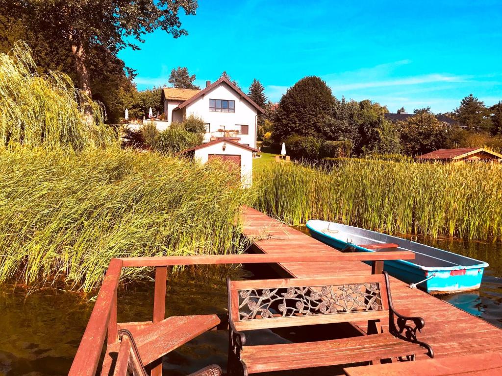a wooden dock with a bench and a boat on the water at Ferienappartement - Haus am See in Woltersdorf