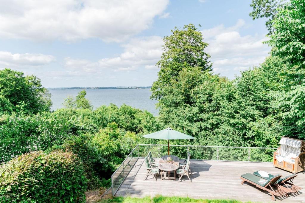 a deck with a table and chairs and an umbrella at Haus Seeblick in Langballig
