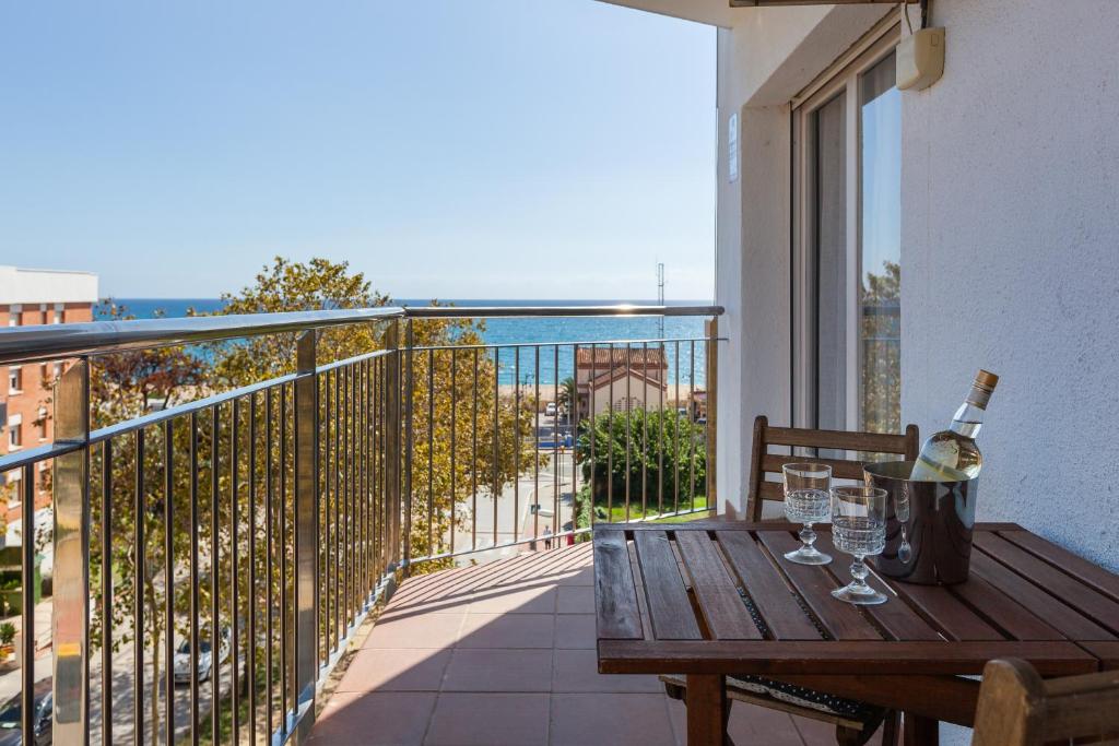 a wooden table with wine glasses on a balcony at Moli Apartment Beach in Canet de Mar