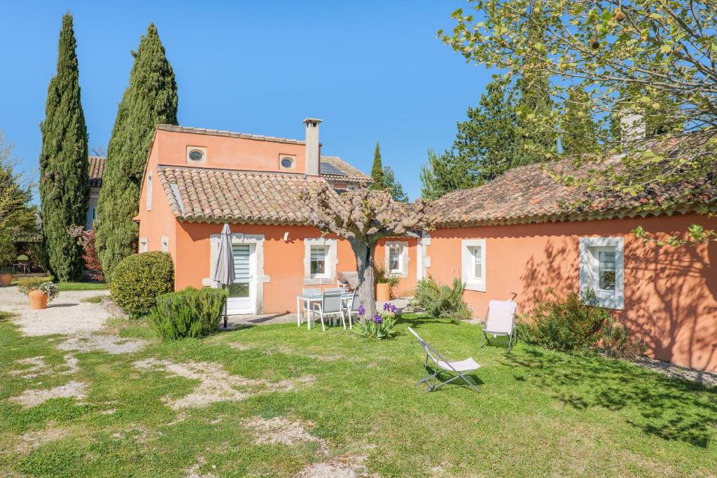 an orange house with a yard with a chair at Le Barry in Tulette