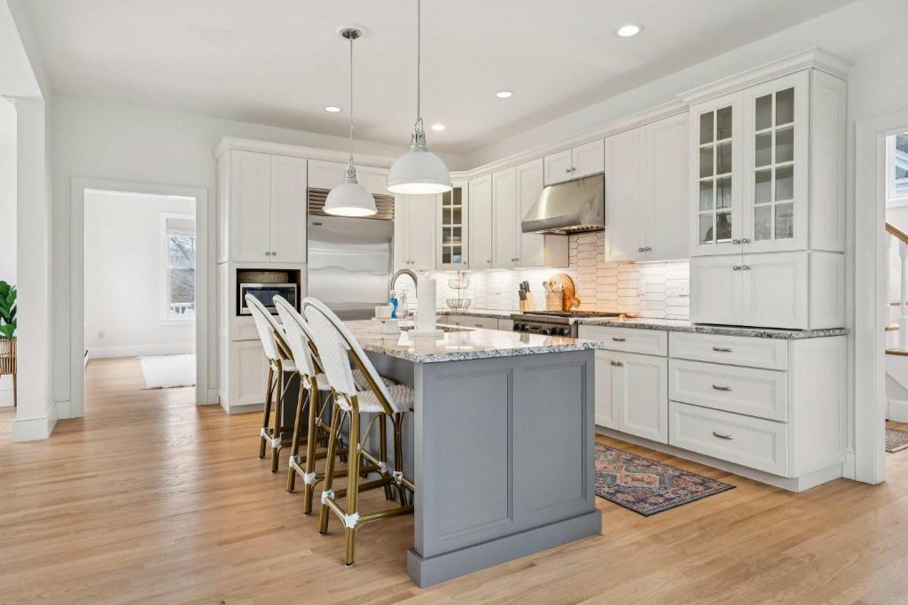 a kitchen with white cabinets and a island with chairs at 3 Mins to York Beach Large Deck Water View in York