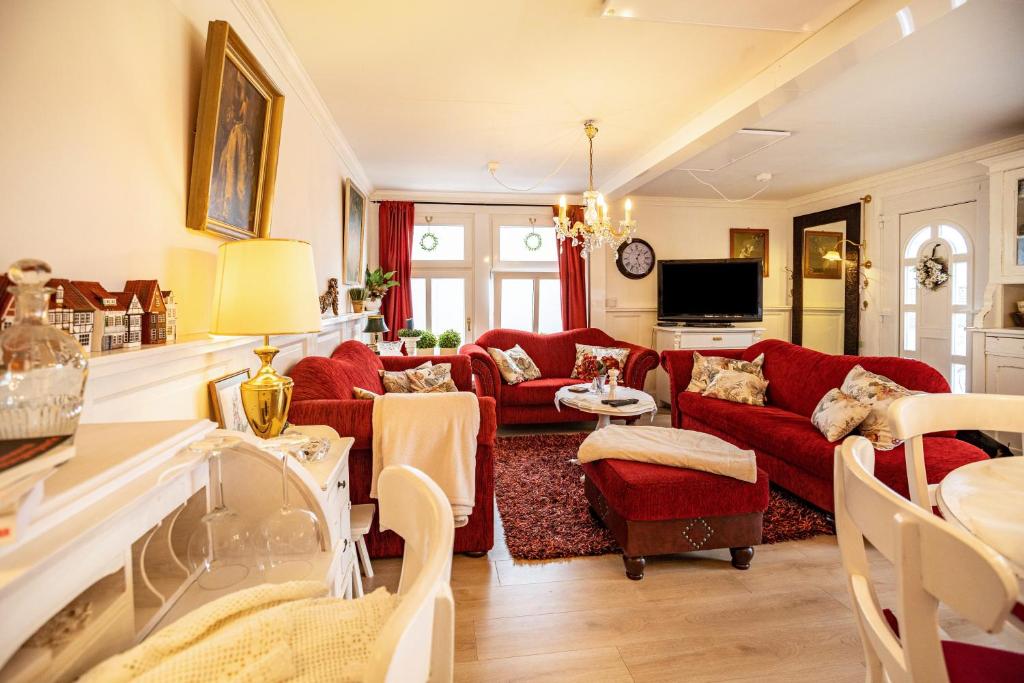 a living room with red couches and a tv at Die Kleine Oase Erste Etage in Stuhr
