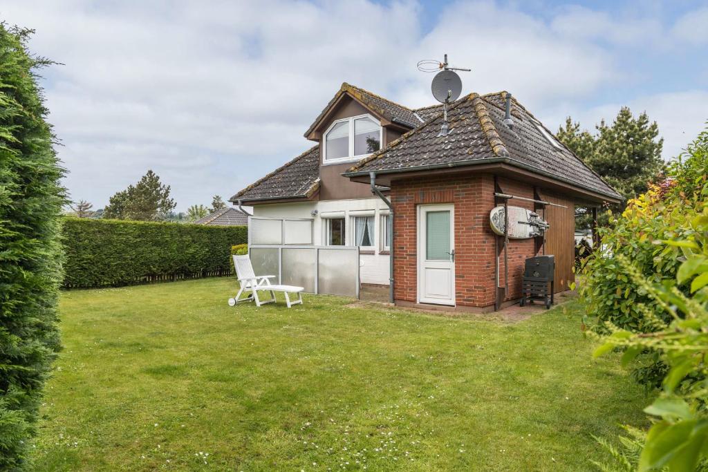 a small house with a yard with a chair at Ferienhaus Herich in Nieblum