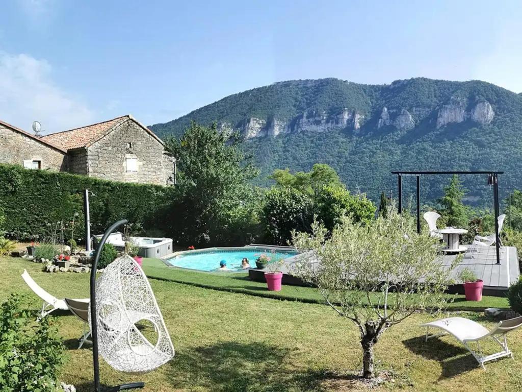a garden with a swimming pool and chairs and a house at Chambres D'hôtes - Au Soleilo in Mostuéjouls