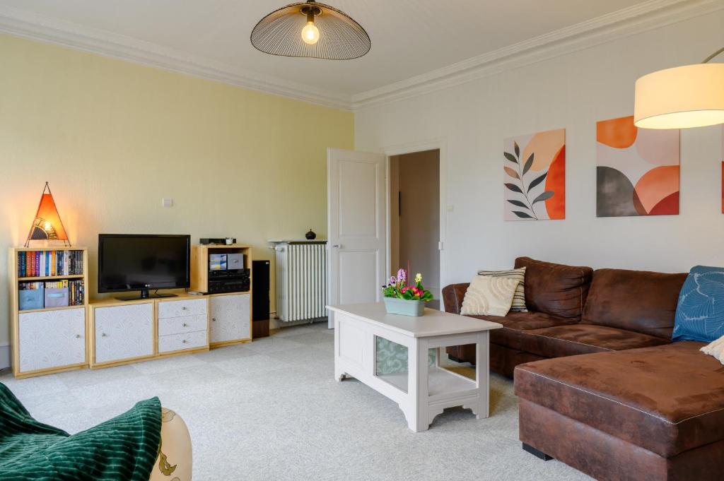 a living room with a couch and a tv at Appartement Le 47 in Thann