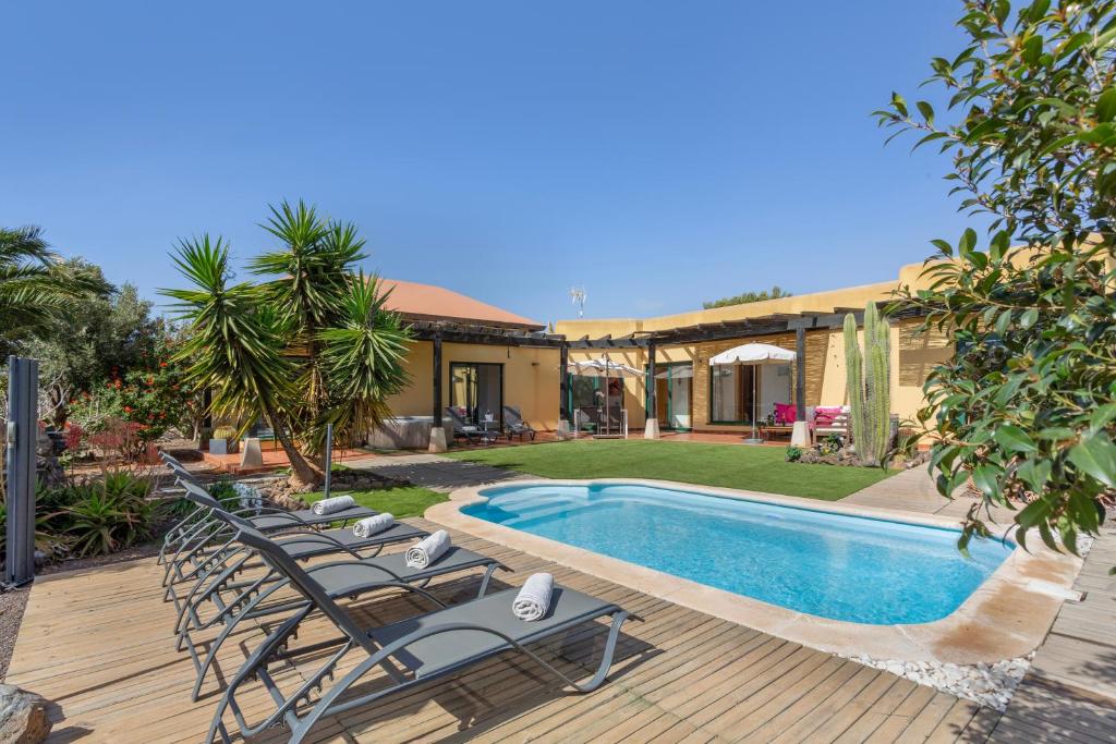a house with a swimming pool with chairs next to it at El refugio in La Oliva