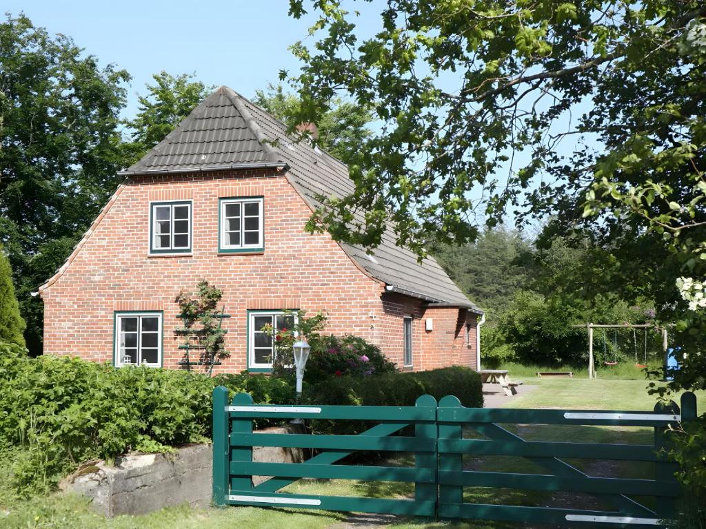 a red brick house with a green fence in front of it at Ferienhaus Drelsdorfer Forst in Drelsdorf