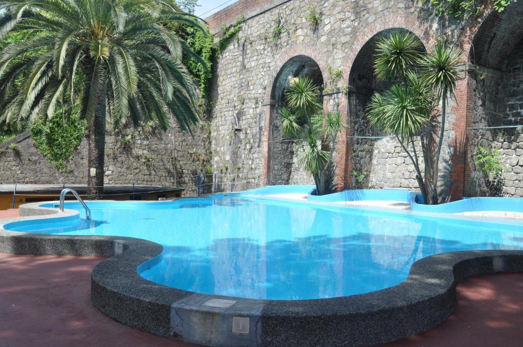 a large blue pool with palm trees in front of a building at Appartamento Monolocale Moneglia 35 in Moneglia