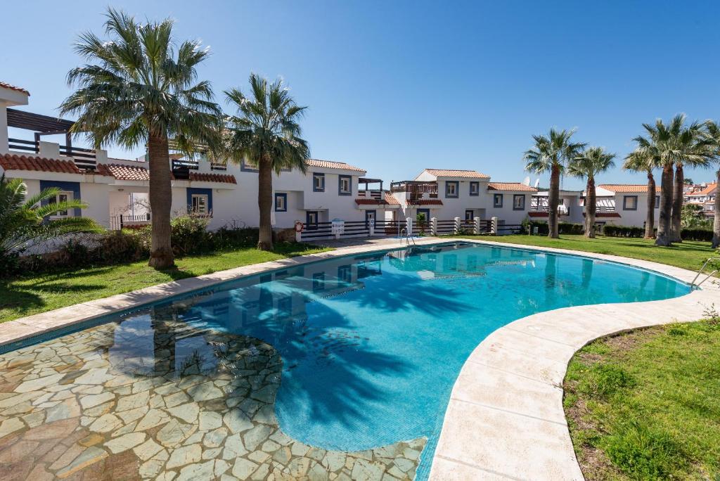 a swimming pool in a yard with palm trees and houses at Atico Duplex con terraza in Manilva
