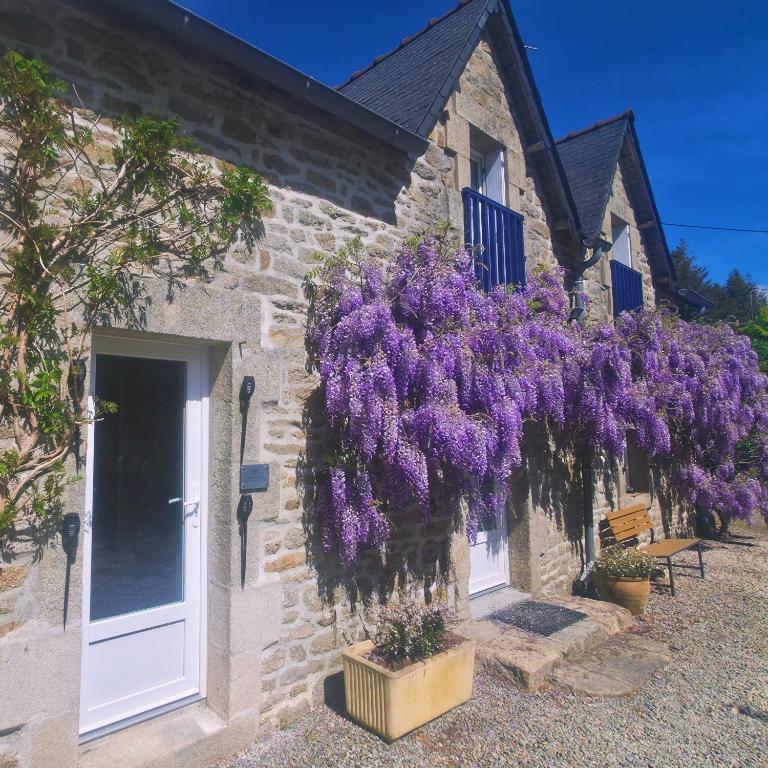 a building with a wreath of purple flowers hanging from it at Ty Kerouannec in Guilligomarcʼh