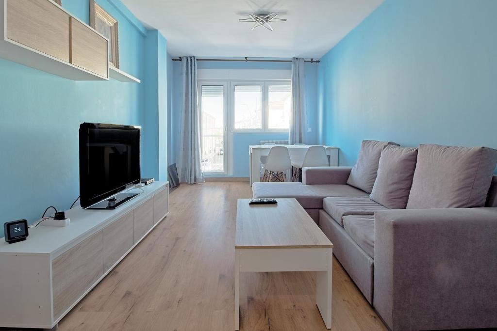 a living room with a couch and a tv at Vivienda Turística Osiris in San Andrés del Rabanedo