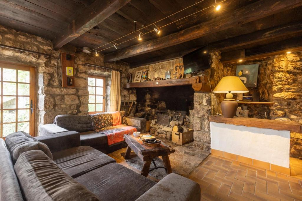 a living room with a couch and a stone fireplace at Les Grisiéres in Montpezat-sous-Bauzon