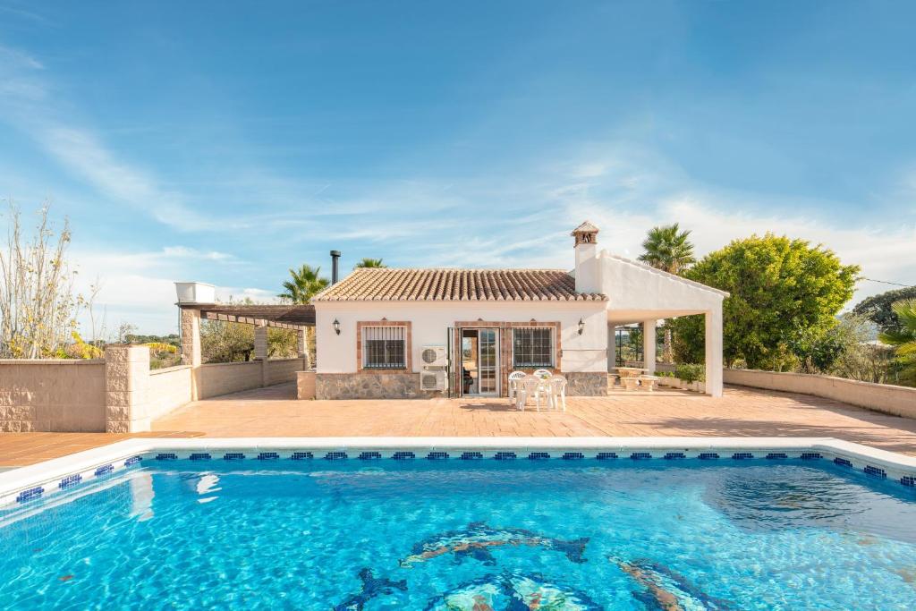 a villa with a swimming pool in front of a house at Chalet andaluz Los Alberos in Coín