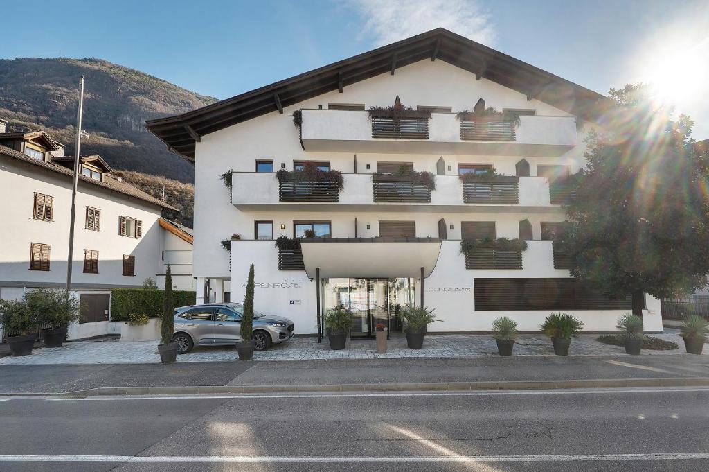 a white building with a car parked in front of it at Residence Alpenrose in Col di Villa
