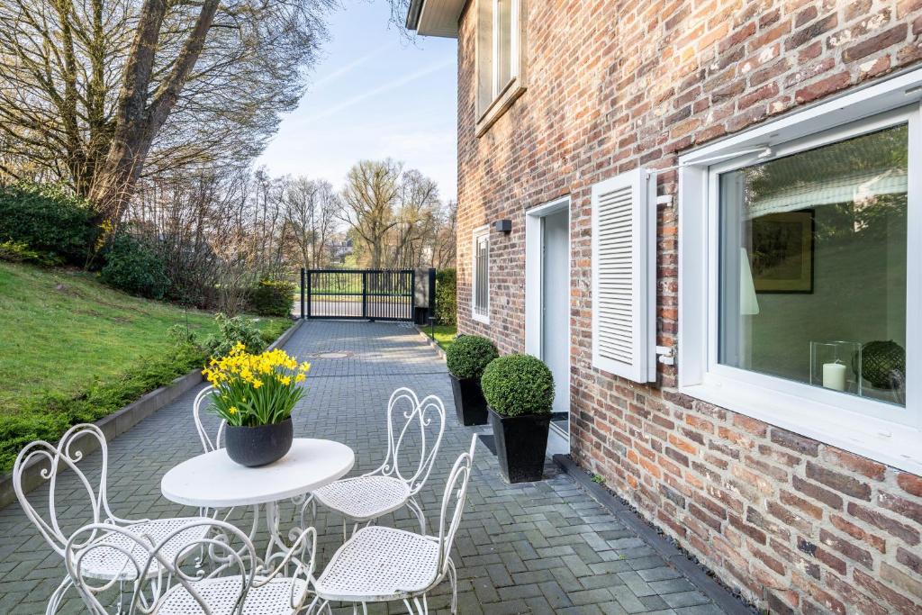 a patio with a table and chairs and a brick building at Ferienwohnung Aachen Süd in Aachen