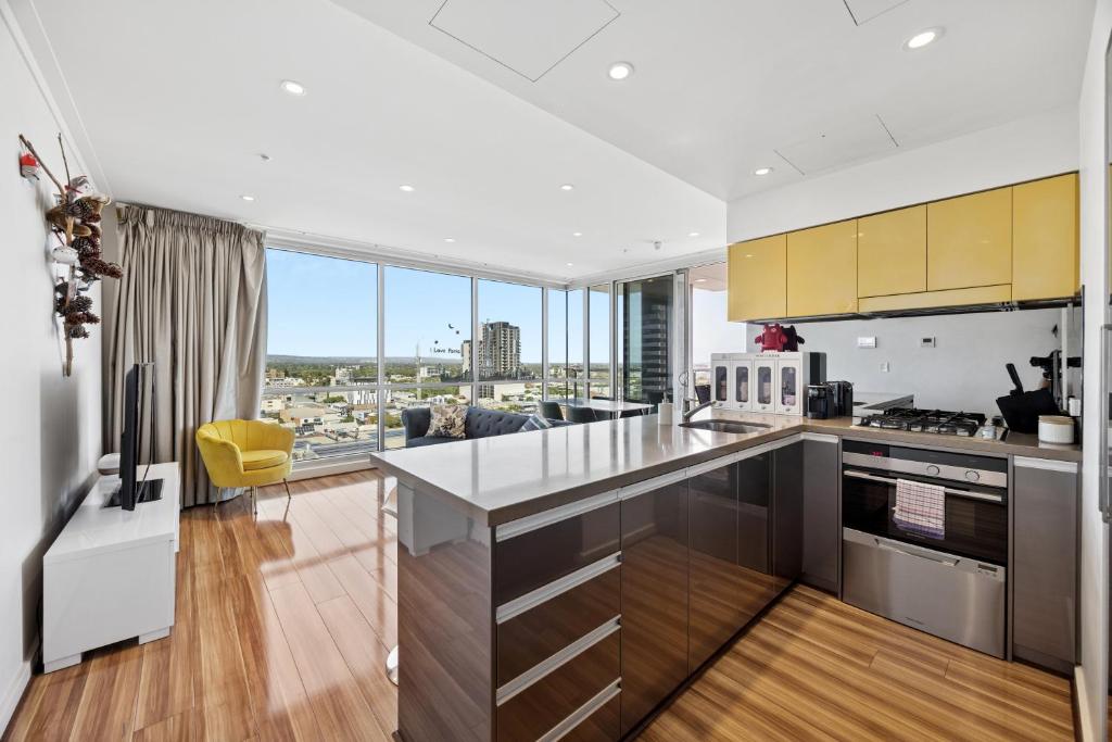 a kitchen with stainless steel appliances and a living room at Adelaide Central Skyline Panoramic Suite Three in Adelaide
