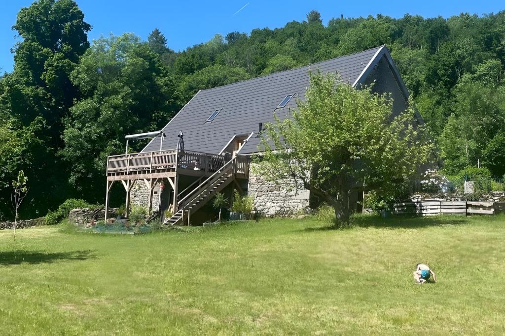 a large house with a deck on a grass field at Gite La Grange De Loey in Méallet