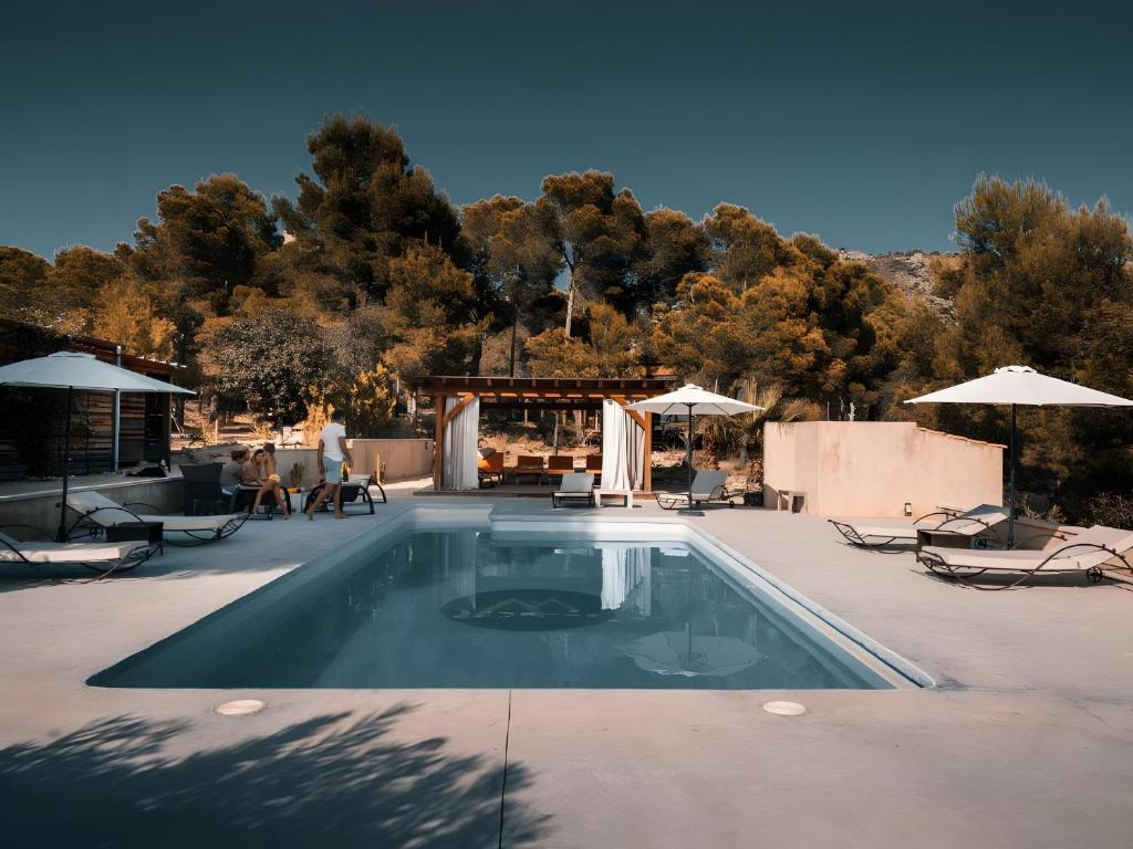a swimming pool with chairs and umbrellas on a patio at Awa Natura in Aigues