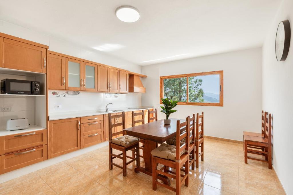 a kitchen with wooden cabinets and a table and chairs at Casa Ñico in Artenara