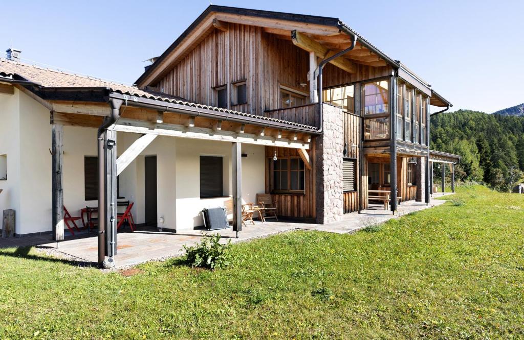 a large wooden house with a deck in a field at Lexn Radein in Redagno