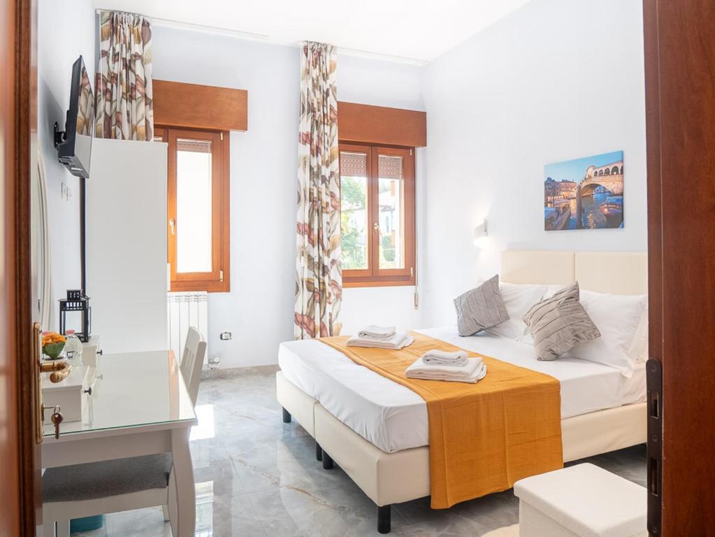 a bedroom with a bed and a desk and two windows at Casa Bella Venezia 1 in Mestre