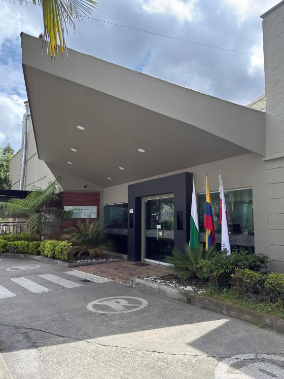 a building with three flags in front of it at Hotel Valle de San Nicolas in Rionegro