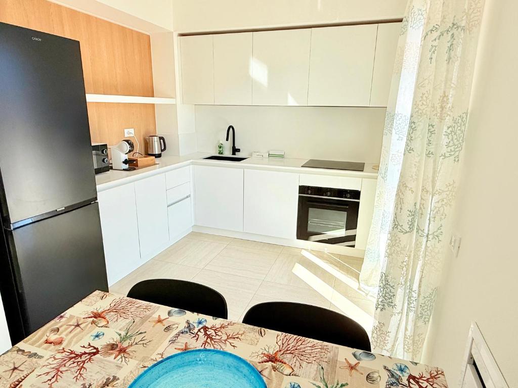 a small kitchen with white cabinets and a table with chairs at Appartamento Mavi in Porto Azzurro
