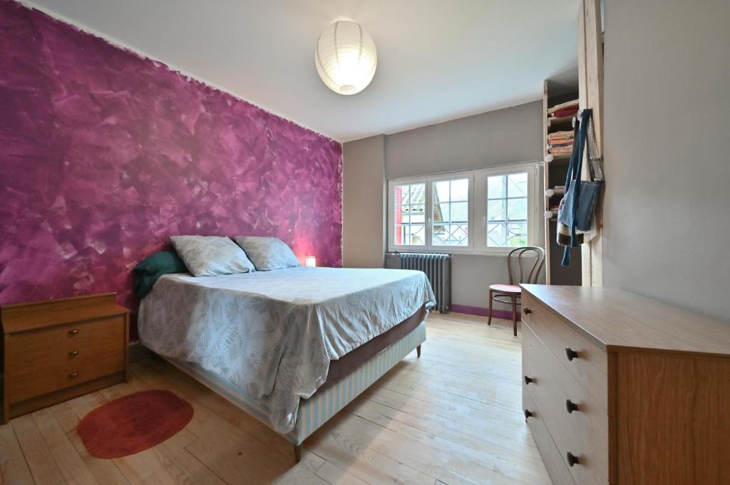 a bedroom with a bed with a purple wall at Pays De L'ours - Pyrénées in Melles