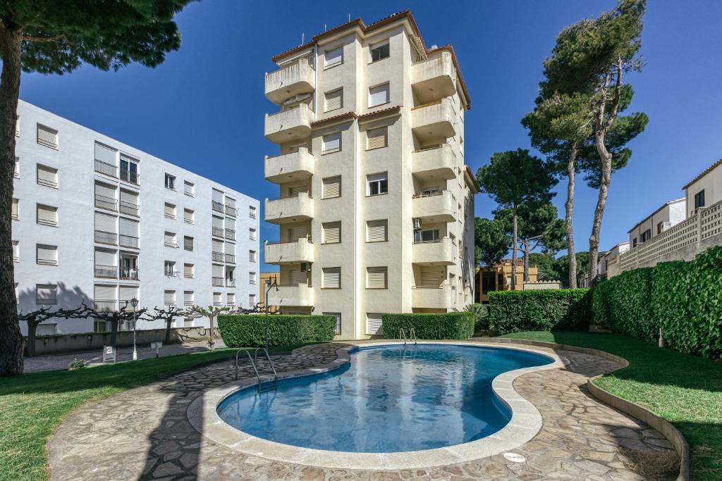an apartment building with a swimming pool in front of a building at San Enrique in L'Escala