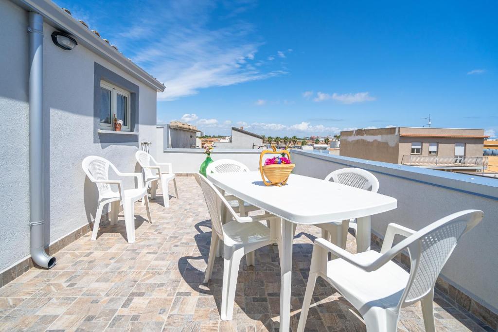 a patio with white chairs and a table on a balcony at Le Quattro Perle Apartments in Pachino