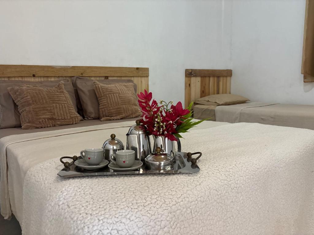 a tray with cups and flowers on a bed at Casa natureza Paraty II in Paraty