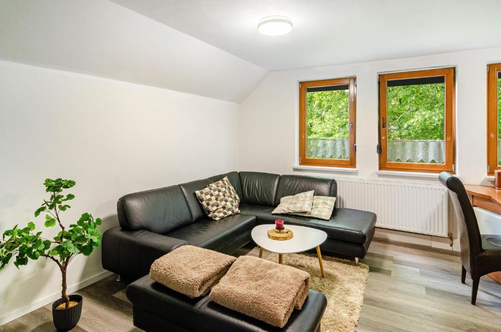 a living room with a black leather couch and a table at Fewo3 Buppeape Saterland in Bollingen
