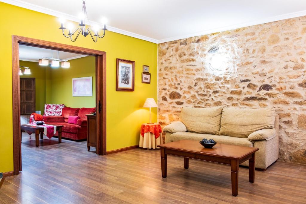 a living room with yellow walls and a stone wall at Casa Rural Doña Manuela in Valdemierque