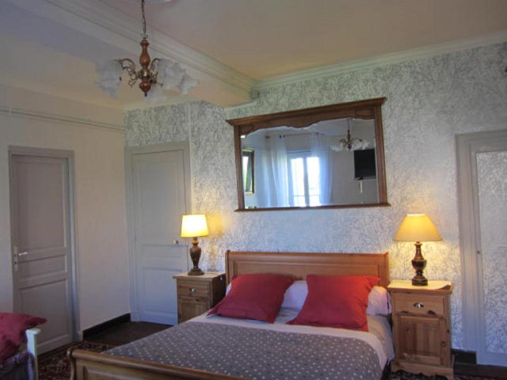 a bedroom with a bed with two red pillows and a mirror at Aude Cité-City in Carcassonne