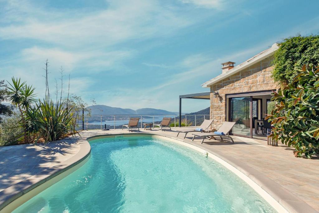 a swimming pool in front of a house at Villa Bumortu in Olmeto