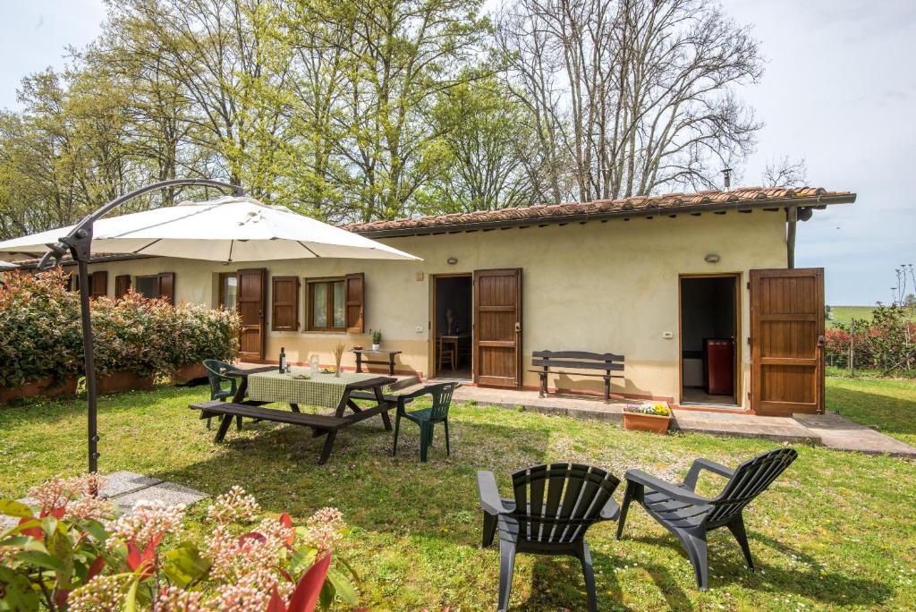 a house with a table and chairs and an umbrella at Faetino - Gallo in Colle di Val d'Elsa