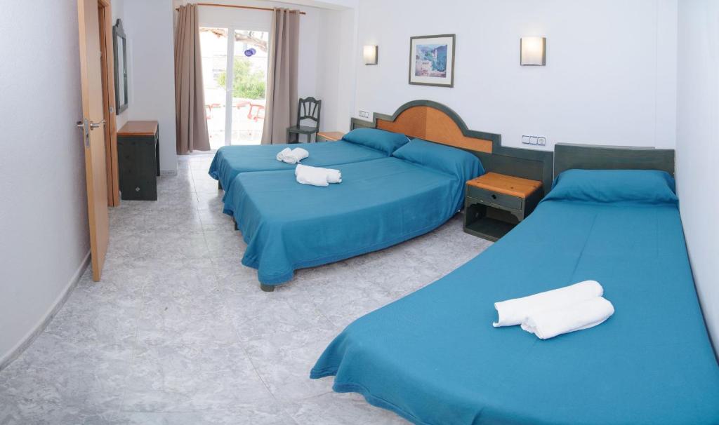 two beds in a bedroom with blue sheets and white towels at Hostal Rosalia in San Antonio