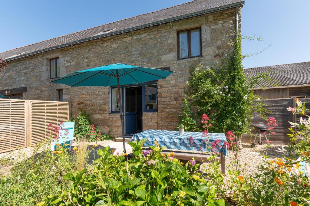 a house with a table and an umbrella in the yard at Domaine de Lestroué - Île d'arz in La Vraie-Croix