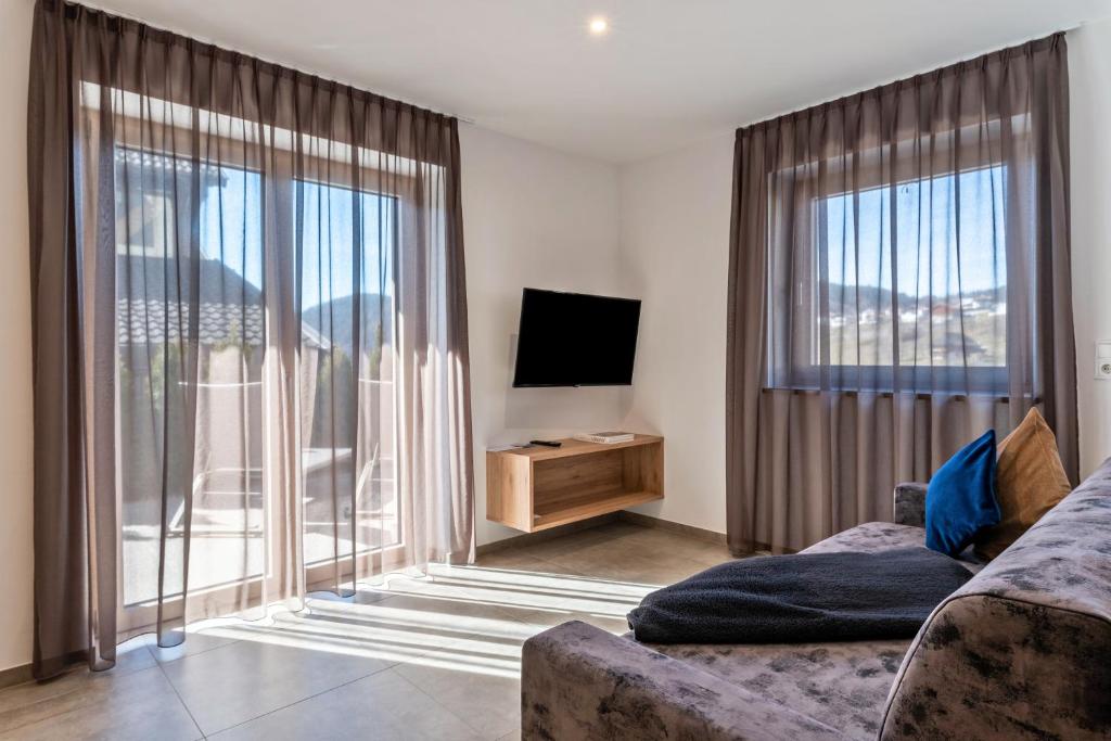 a living room with a couch and a television at Aster Moments Apt Moritz in San Genesio Atesino