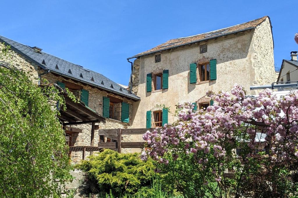 an old building with green shuttered windows and purple flowers at Le Cottage des Pléiades in Les Angles