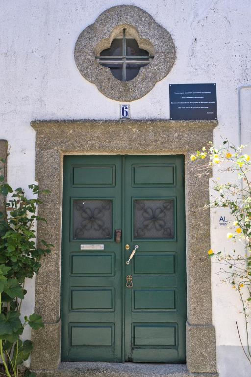 a green door in a building with a sign above it at Casa Pedra da Paciência in Monsanto