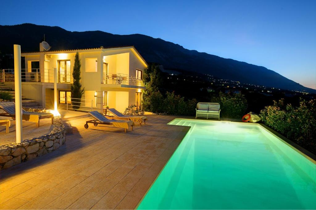 a villa with a swimming pool in front of a house at Villa Kteni Ideales Resort in Kefallonia
