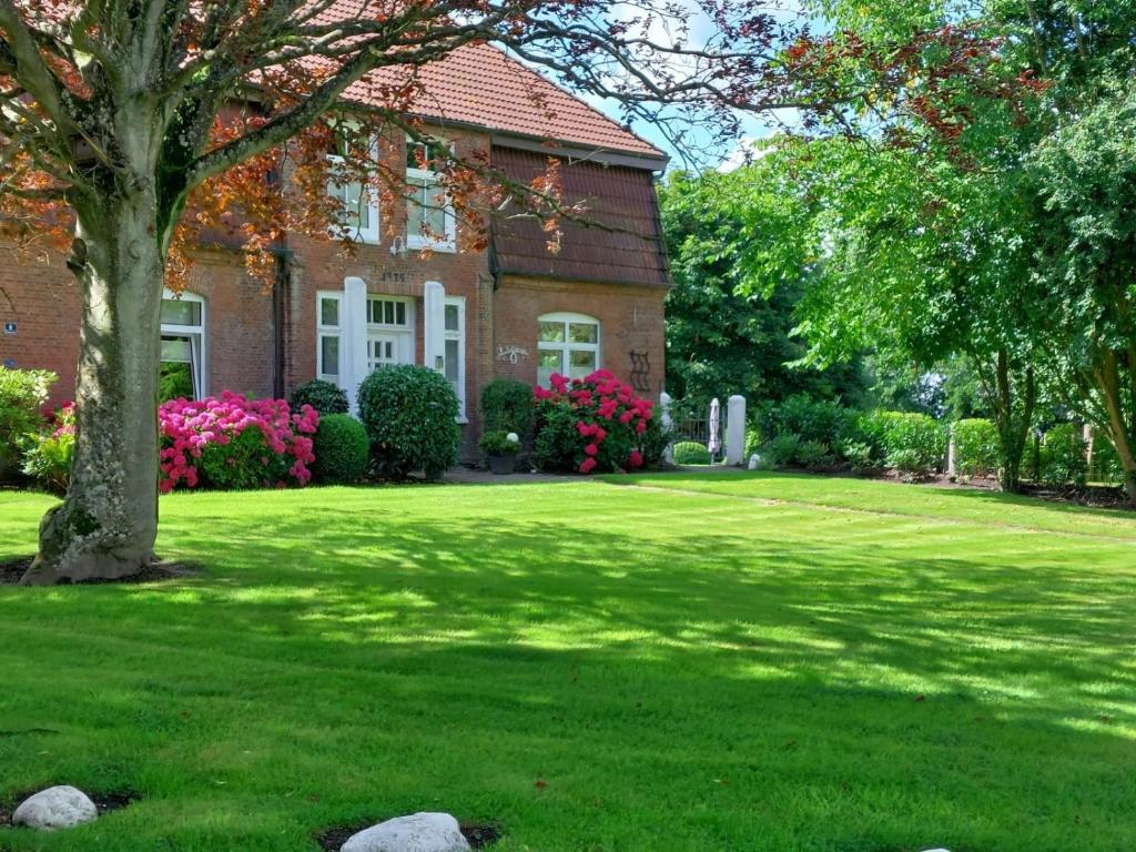 a brick house with a green yard with a tree at Ferienwohnung Obenauf in Oesterwurth