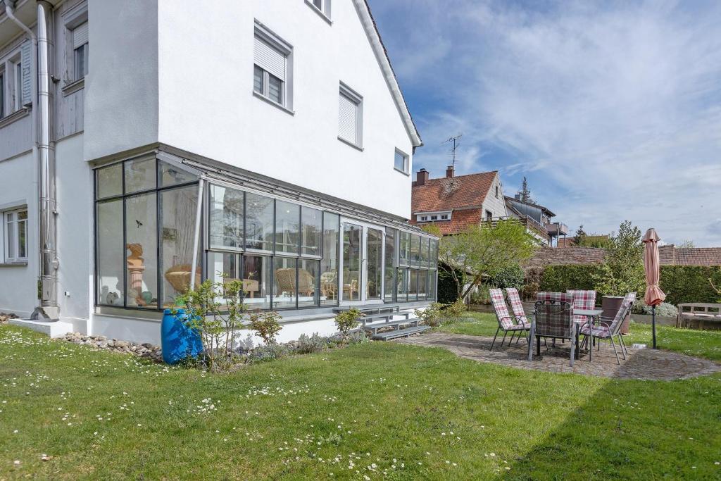 a white house with glass windows and a table and chairs at Stricker in Markelfingen