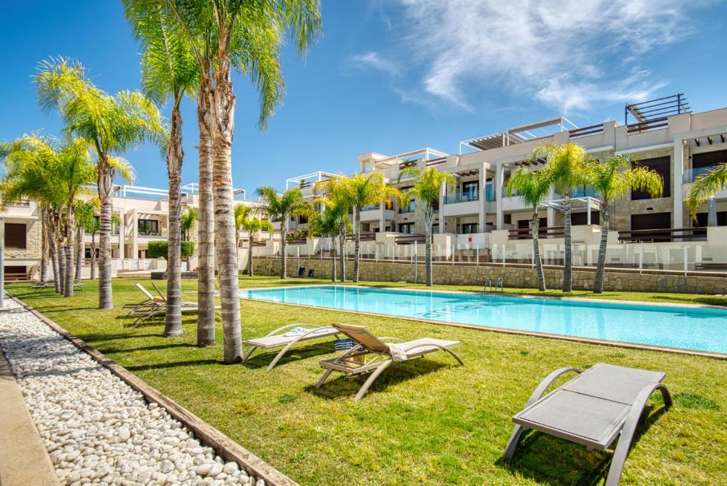 a swimming pool with palm trees and a building at Casa Mar y Sol in Los Belones