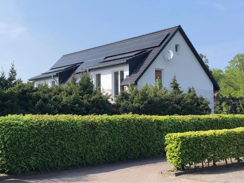 a white house with a black roof and some bushes at Ostseerauschen in Hohwacht