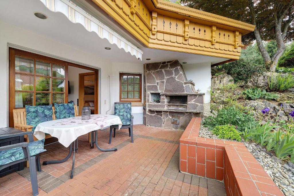 a patio with a table and chairs and a stone fireplace at Ferienwohnung am Steinbach in Albstadt