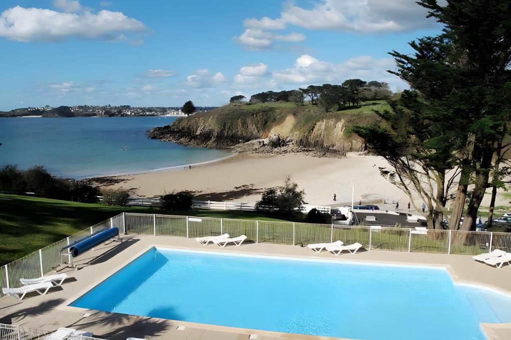 a swimming pool with a view of a beach at Maison dans résidence mer - piscine in Loc-Maria-Plouzané
