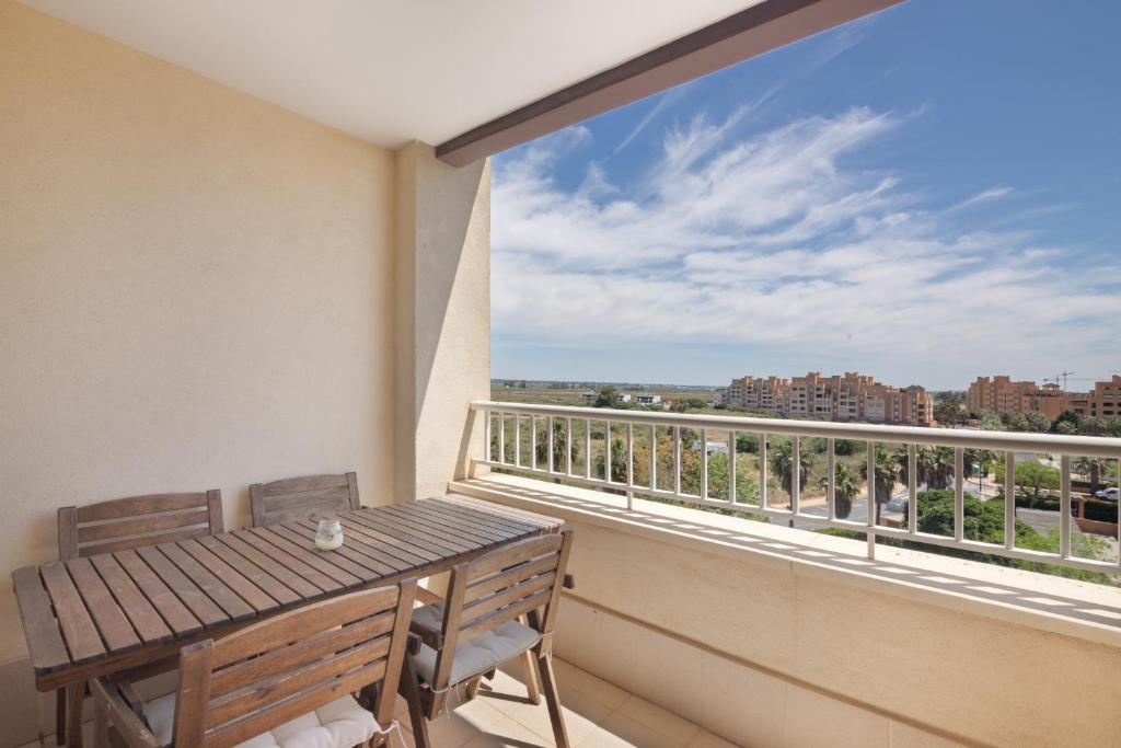a balcony with a wooden table and a large window at Apartamento en Isla Canela in Ayamonte