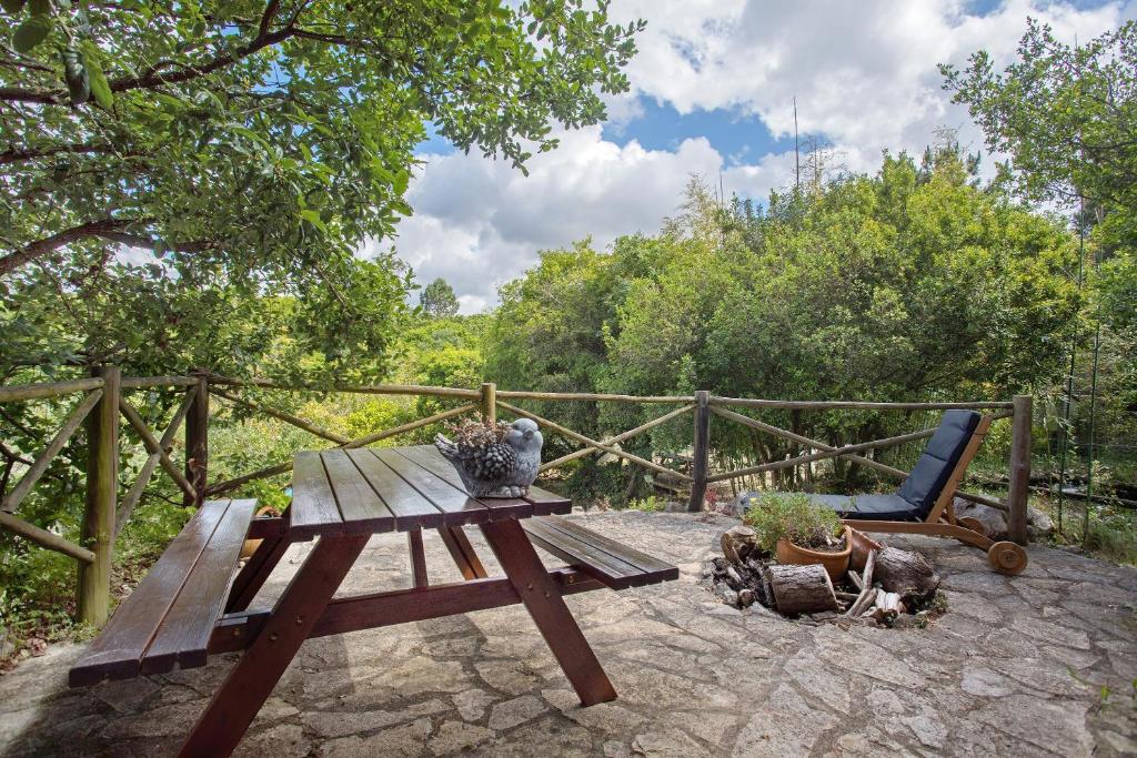 a wooden picnic table and a chair on a patio at Quinta do Castelo - Casa de Pedra in Reguengo Grande